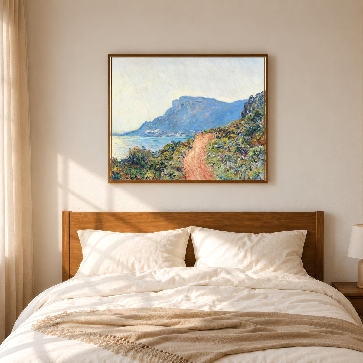 Framed art print of The Corniche near Monaco by Claude Monet, in a slim wood frame above a bed in a sunlit bedroom