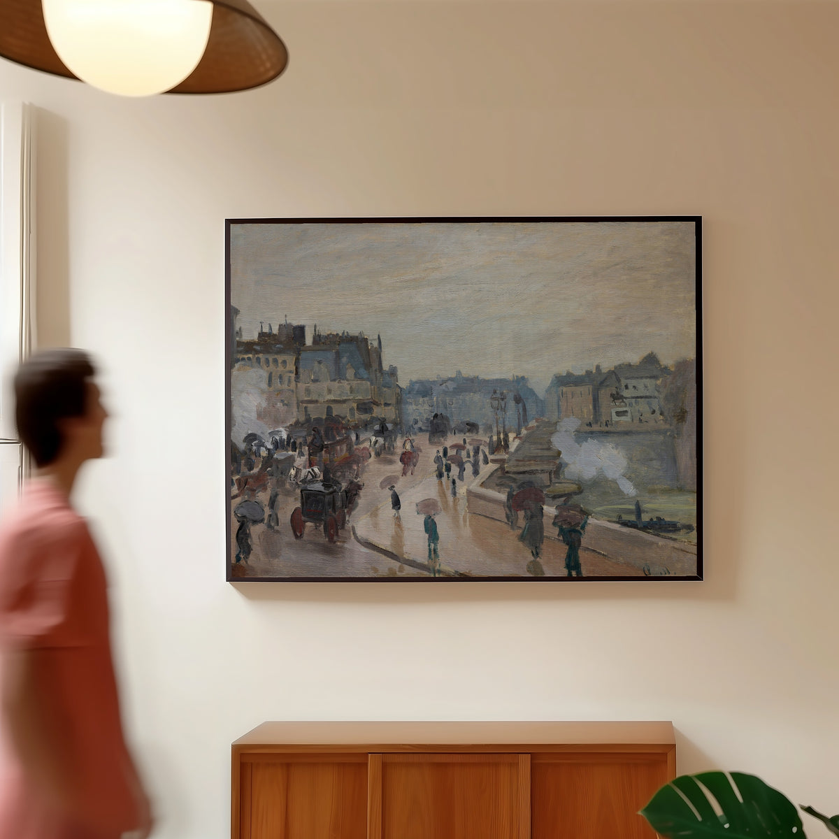 Framed art print of The Pont Neuf by Claude Monet, in a slim black frame on a warm wall in a sunlit room
