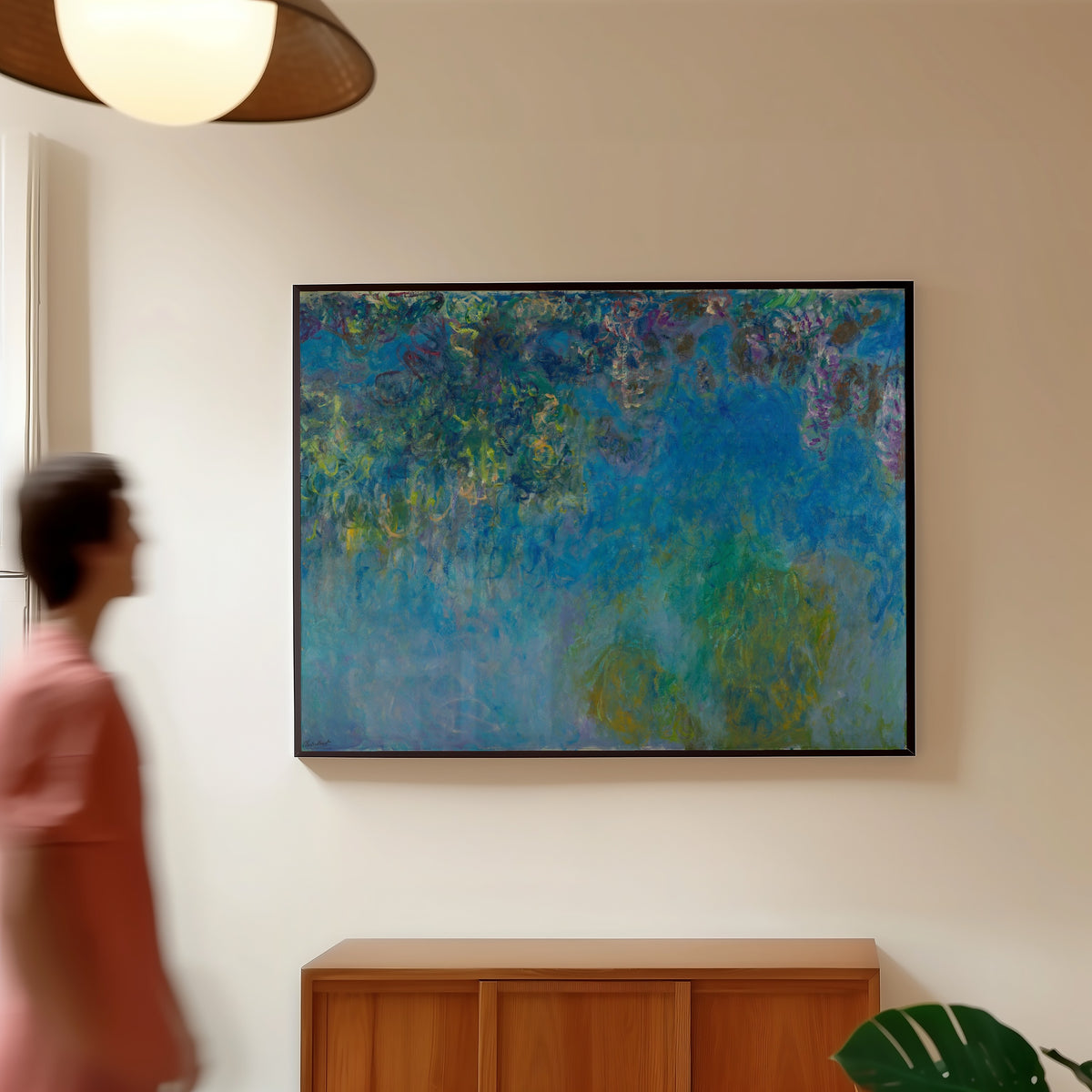 Framed art print of Wisteria by Claude Monet, in a slim black frame on a warm wall in a sunlit room