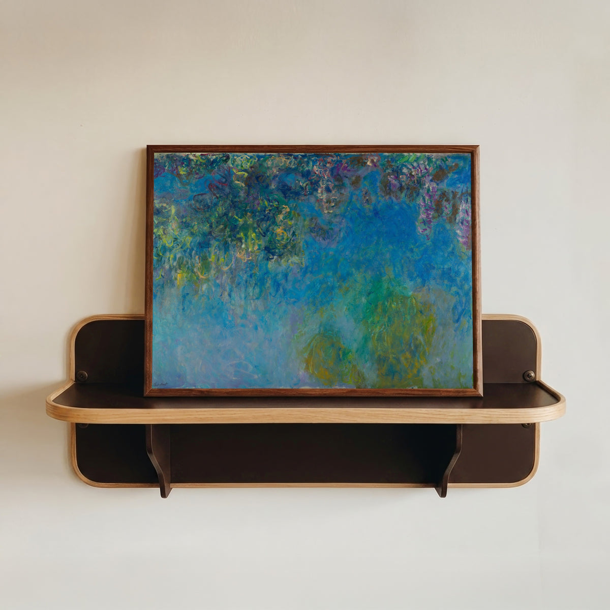 Framed art print of Wisteria by Claude Monet, in a dark wood frame resting on a wall shelf