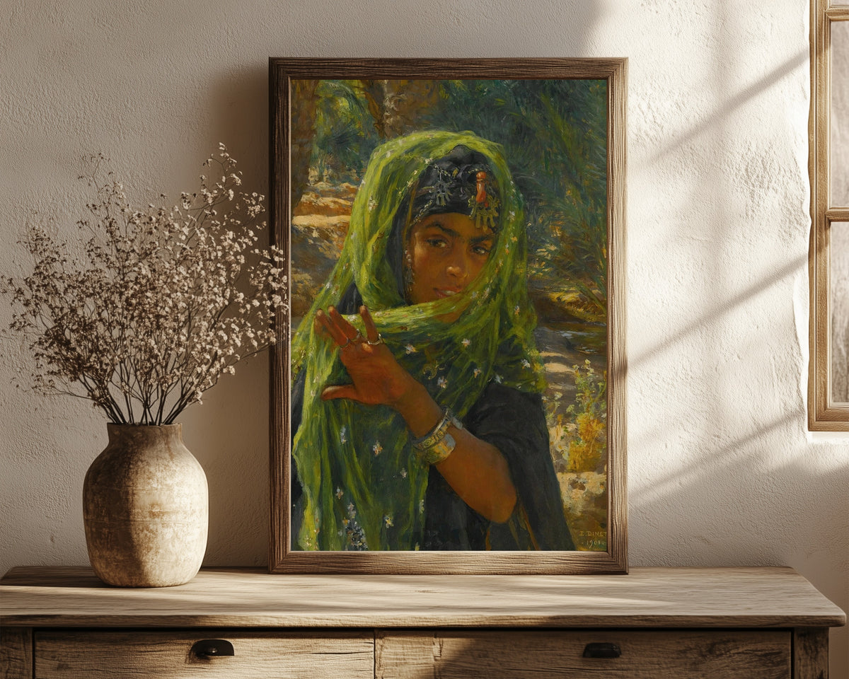 Framed art print of The Girl in the Green Scarf by Nasreddine Dinet, in a dark wood frame leaning on a rustic console beside dried flowers