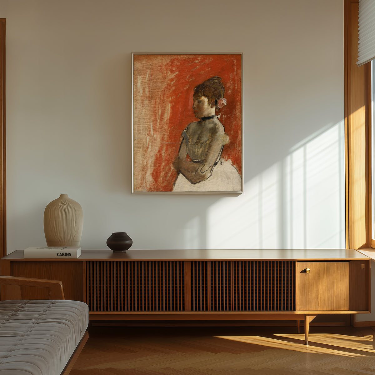 Framed art print of Ballet Dancer with Arms Crossed by Edgar Degas, in a thin light frame on a sunlit wall above a wooden sideboard