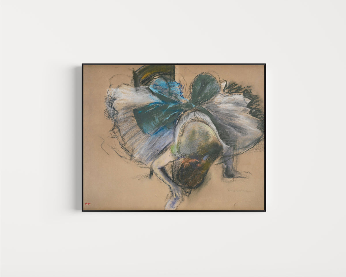 Framed art print of Dancer Adjusting Her Slipper (Blue and Green Bow) by Edgar Degas, in a slim black frame on a plain white wall