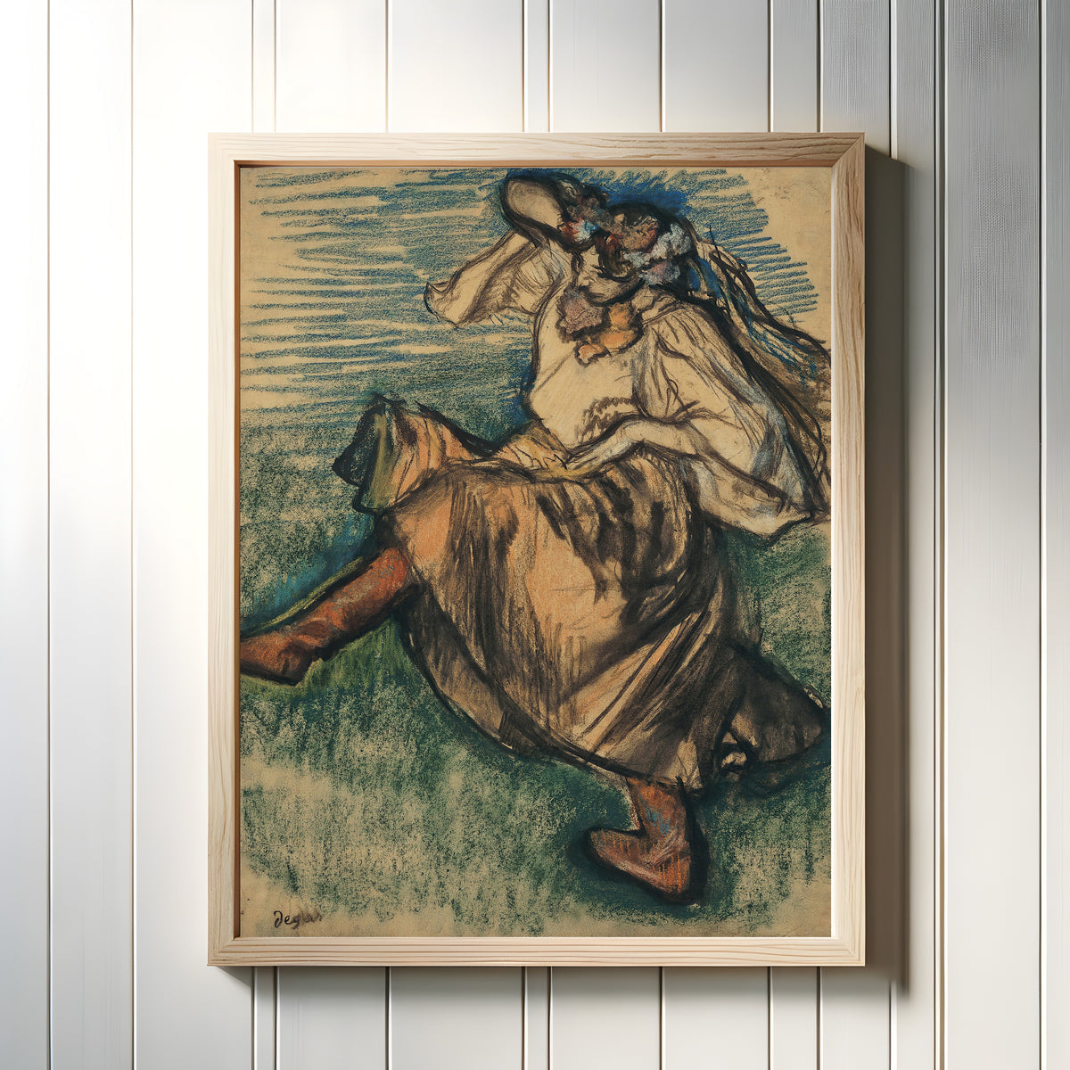 Framed art print of Dancer in Ukrainian Dress by Edgar Degas, in a light wood frame on a white panelled wall