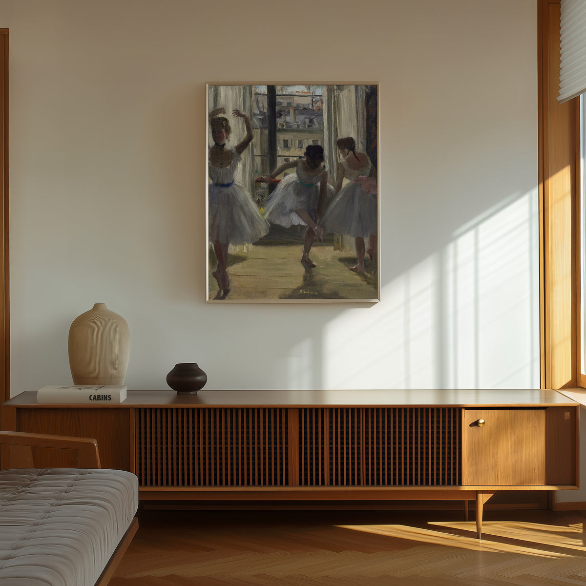 Framed art print of Danseuses dans une salle d’exercice (Trois Danseuses) by Edgar Degas, in a thin light frame on a sunlit wall above a wooden sideboard