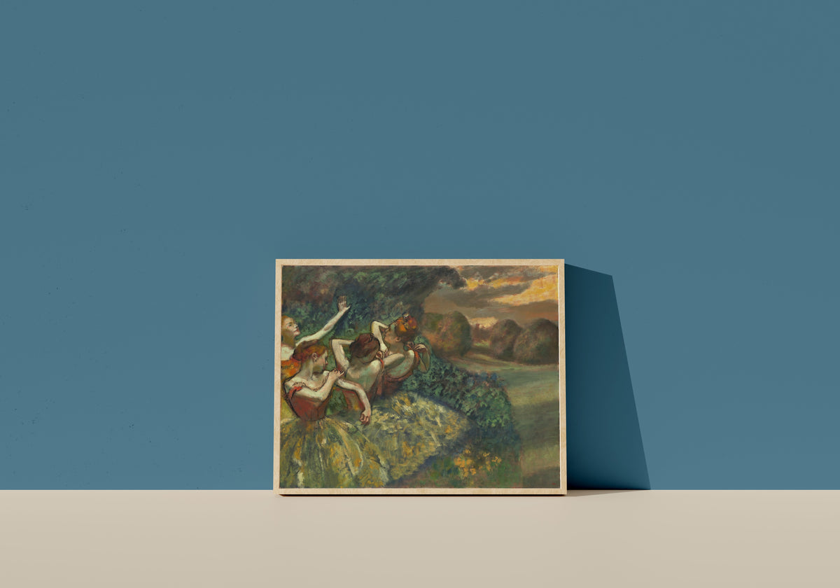 Framed art print of Four Dancers by Edgar Degas, in a light wood frame leaning on a blue wall