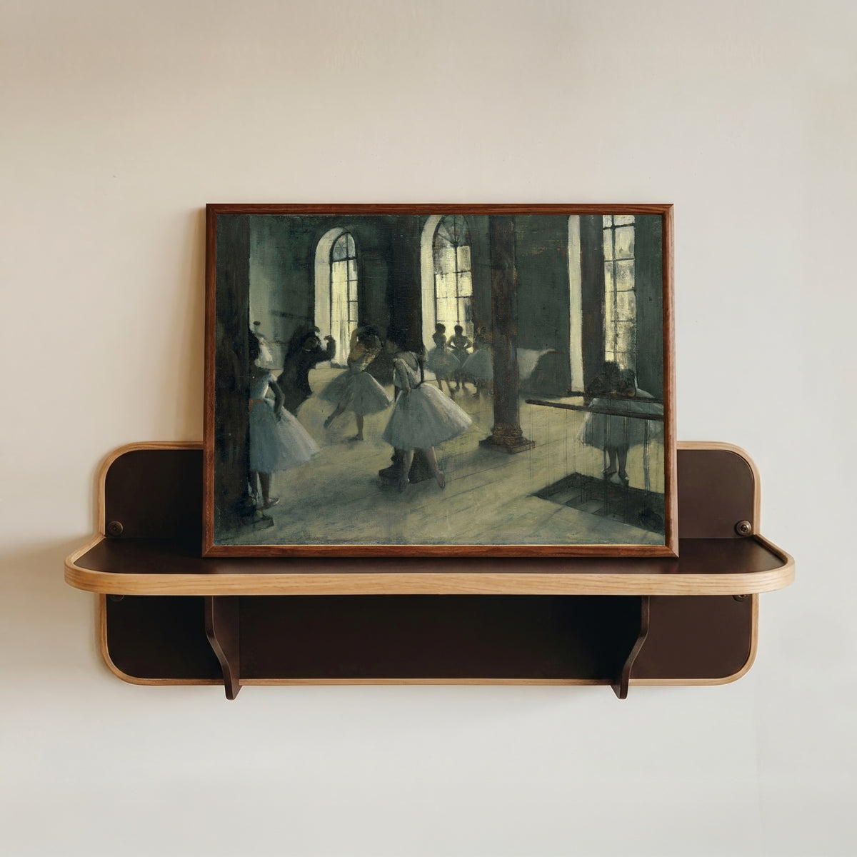 Framed art print of La Répétition au foyer de la danse by Edgar Degas, in a dark wood frame resting on a wall shelf