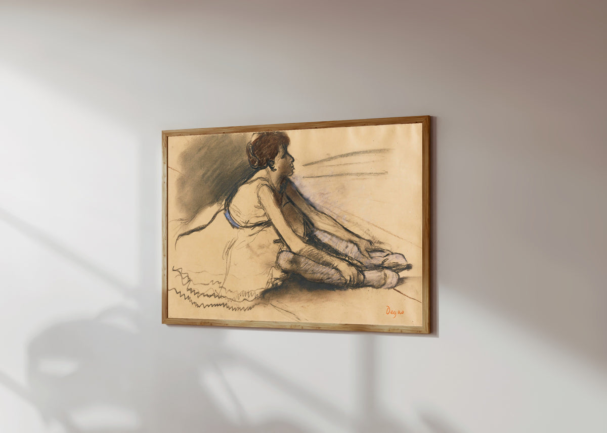 Framed art print of Le repos de la danseuse by Edgar Degas, in a light wood frame on a sunlit white wall, seen at a slight angle