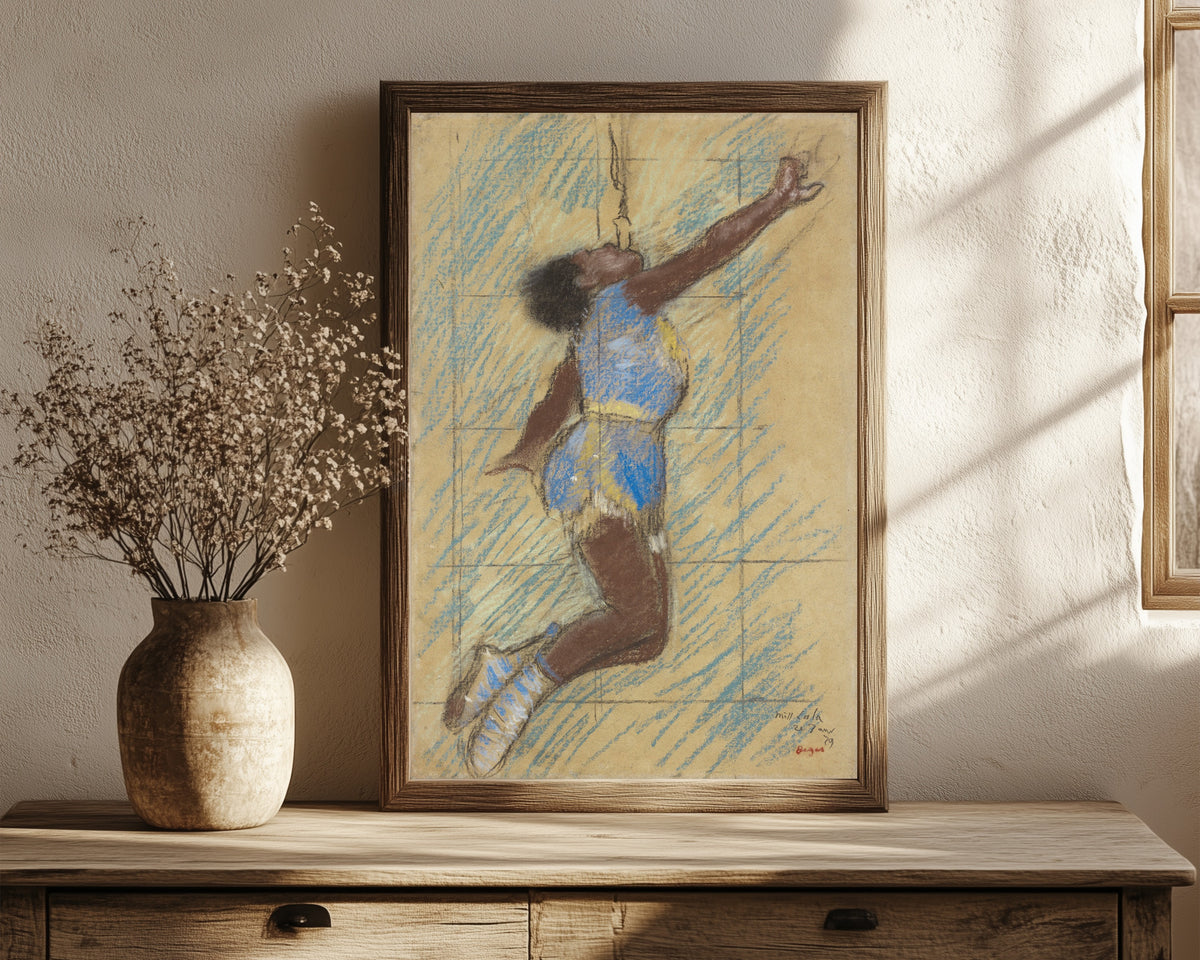 Framed art print of Miss Lala at the Fernando Circus by Edgar Degas, in a dark wood frame leaning on a rustic console beside dried flowers