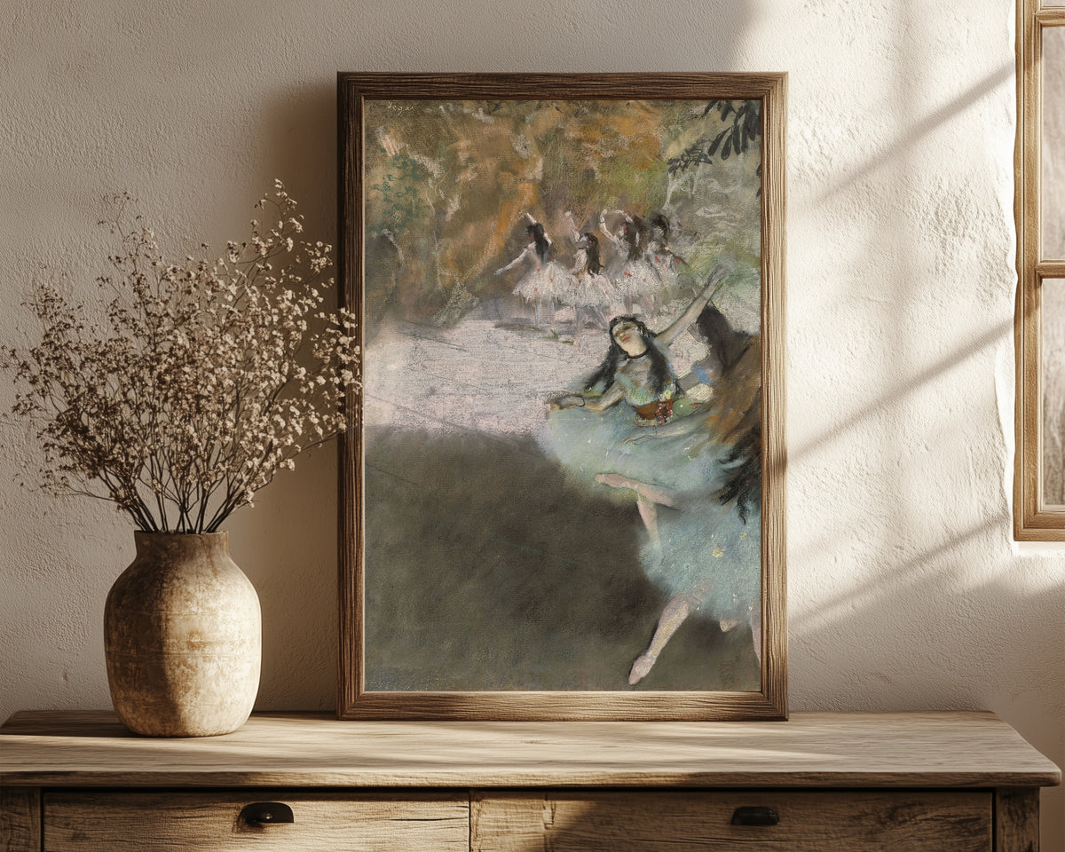 Framed art print of On the Stage by Edgar Degas, in a dark wood frame leaning on a rustic console beside dried flowers