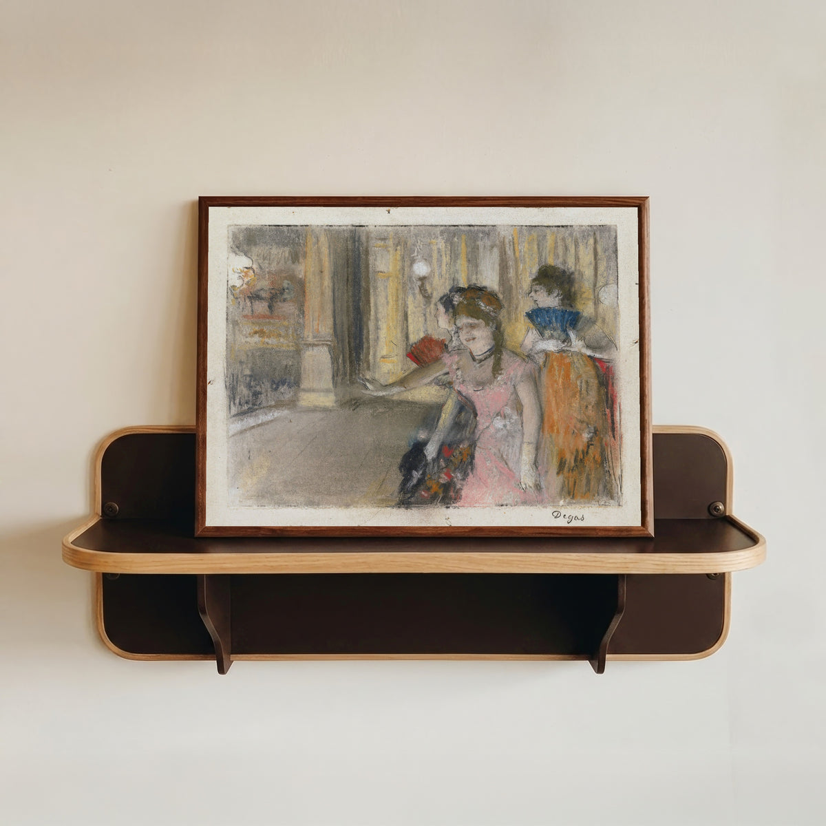 Framed art print of Singers on the Stage by Edgar Degas, in a dark wood frame resting on a wall shelf