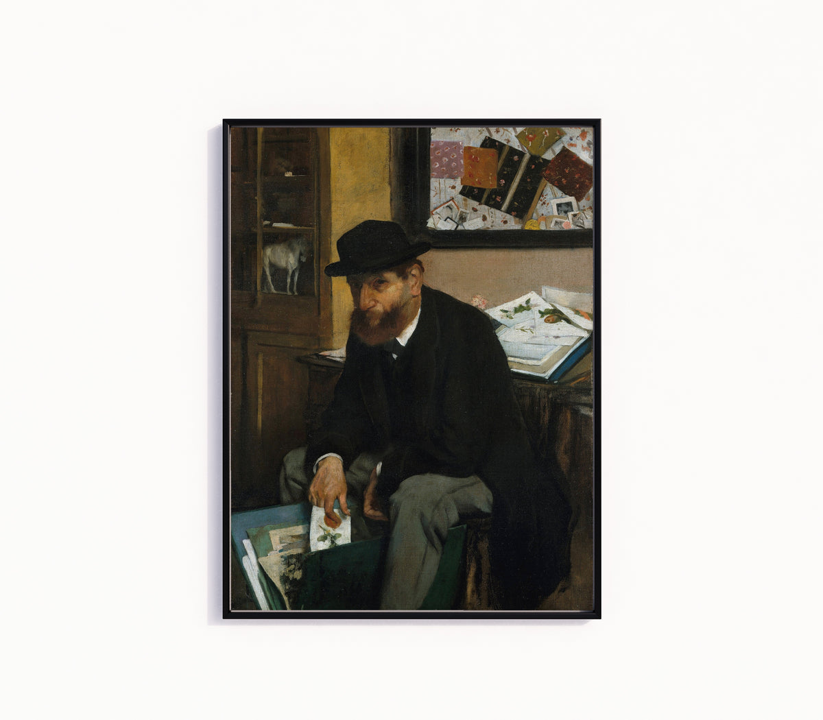 Framed art print of The Collector of Prints by Edgar Degas, in a slim black frame on a plain white wall