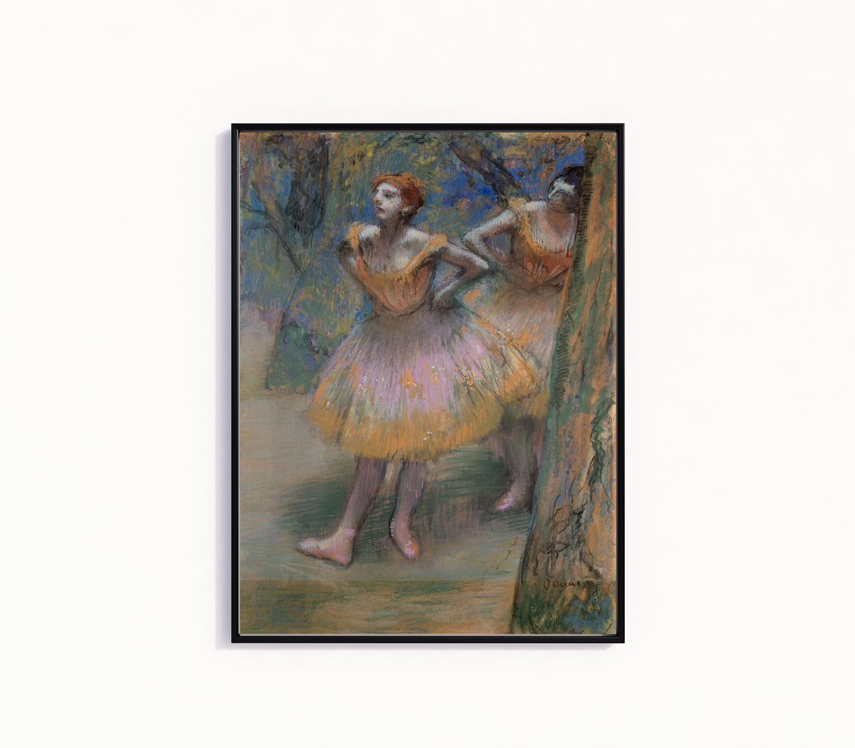 Framed art print of Two Dancers (Lilac and Orange Tutus) by Edgar Degas, in a slim black frame on a plain white wall
