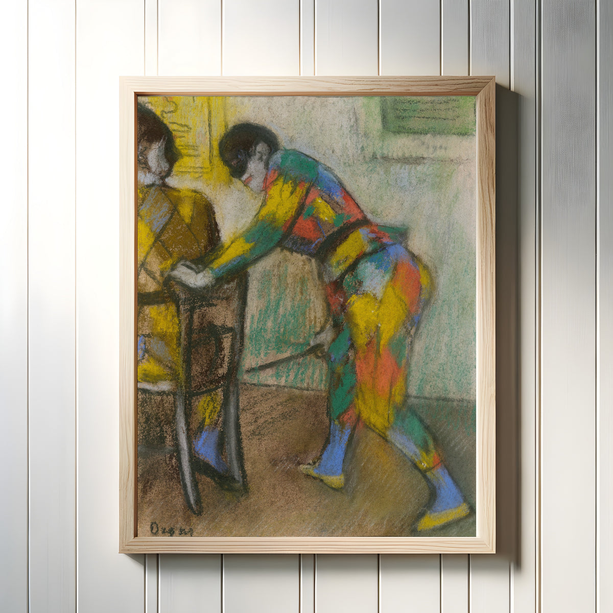 Framed art print of Two Harlequins by Edgar Degas, in a light wood frame on a white panelled wall