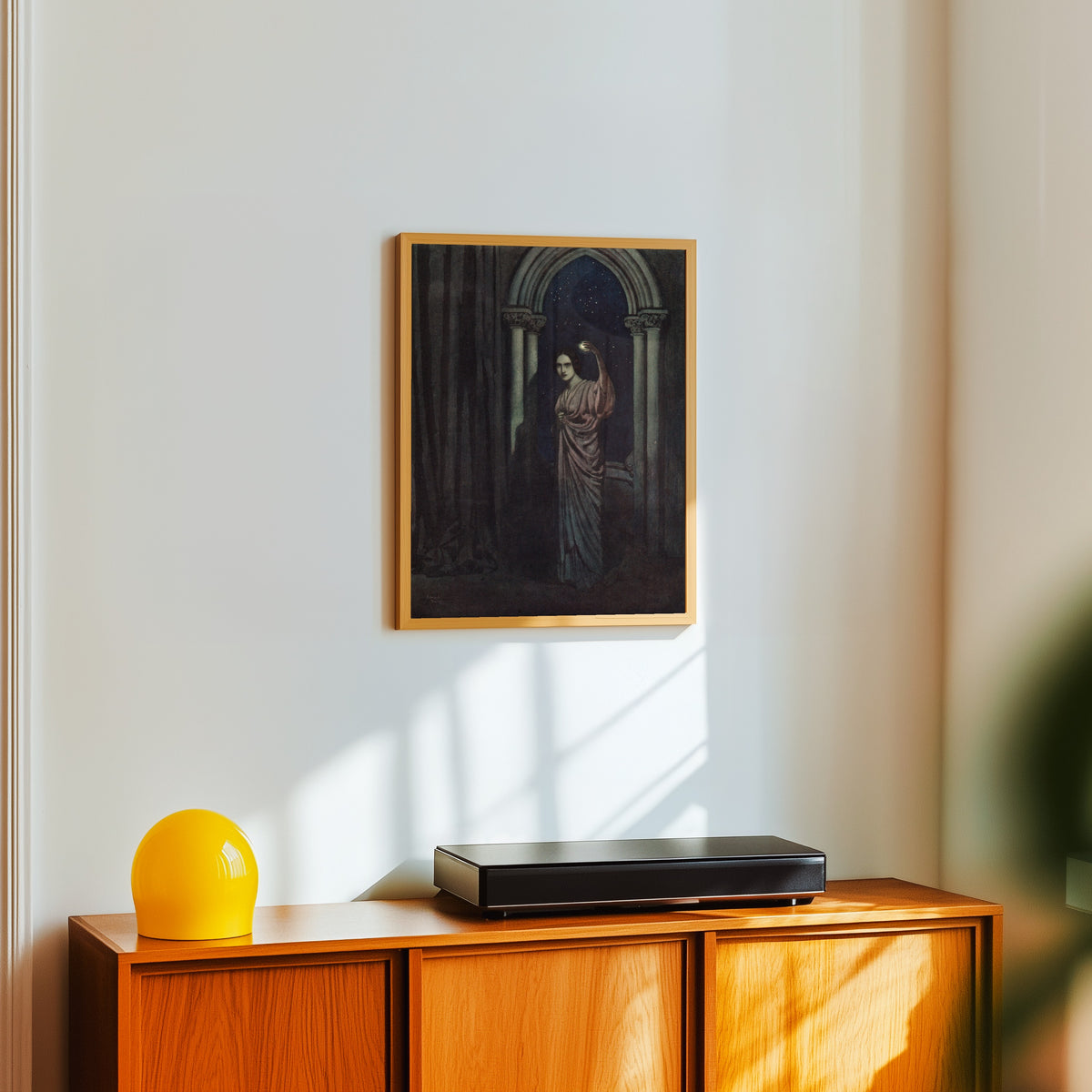 Framed art print of The Bells and Other Poems: To Helen by Edmund Dulac, in a light wood frame on a white wall above an orange sideboard