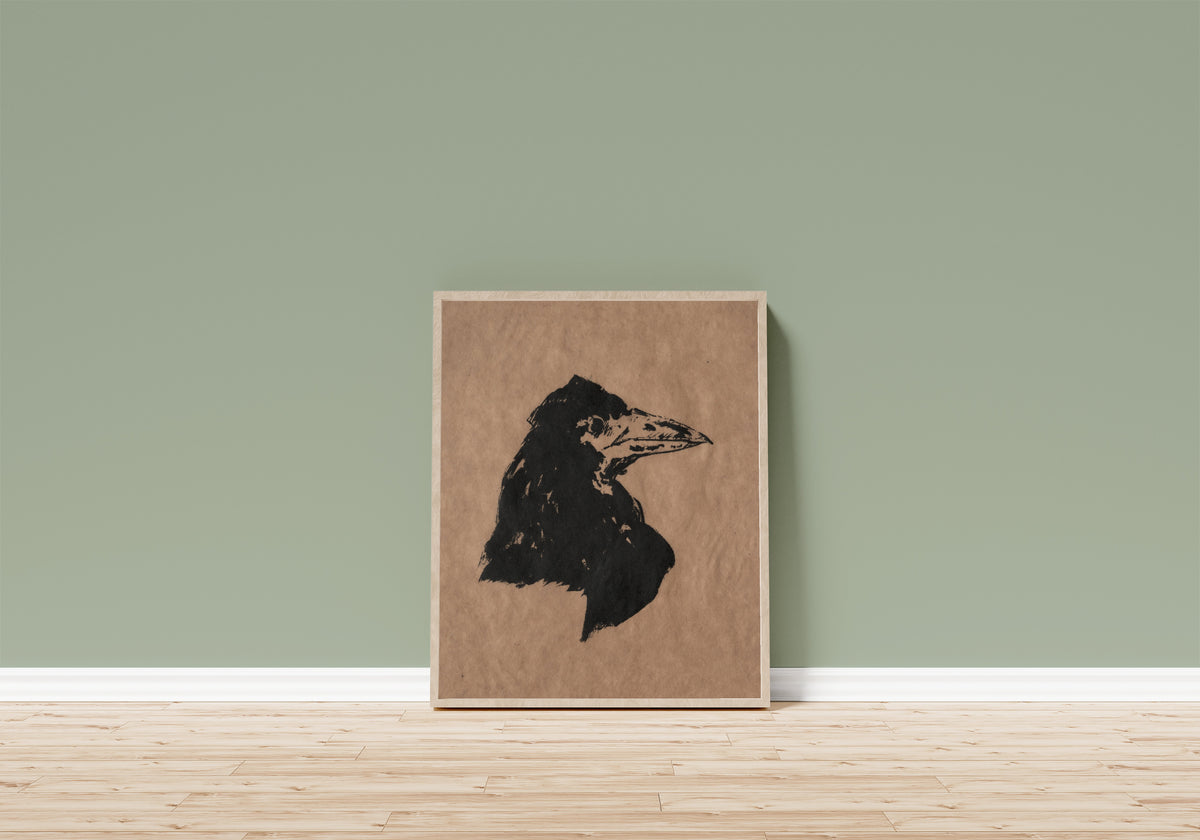 Framed art print of Raven's Head in Profile by Édouard Manet, in a light wood frame leaning on a sage green wall above a wooden floor