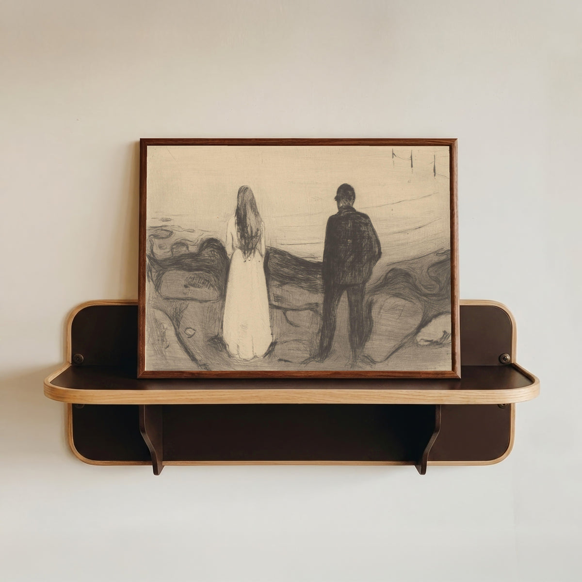 Framed art print of Two People (The Lonely Ones) by Edvard Munch, in a dark wood frame resting on a wall shelf