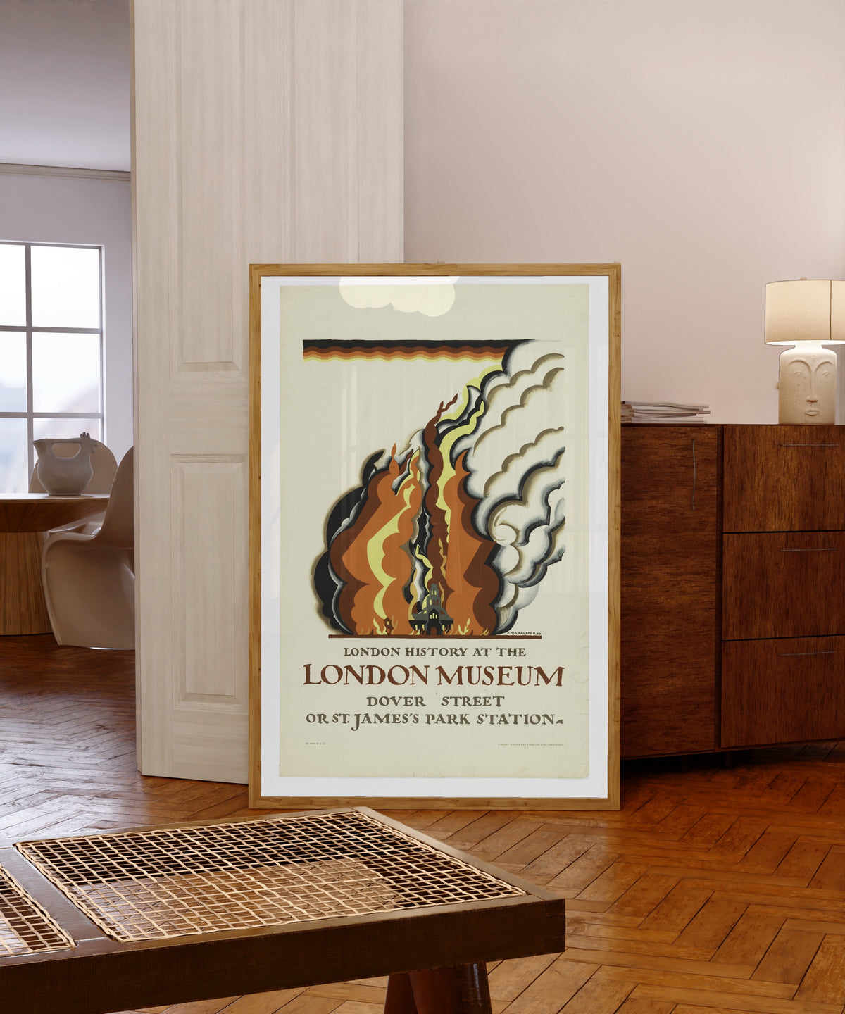 Framed art print of London History at the London Museum by Edward McKnight Kauffer, in a light wood frame leaning in a warm room with a parquet floor