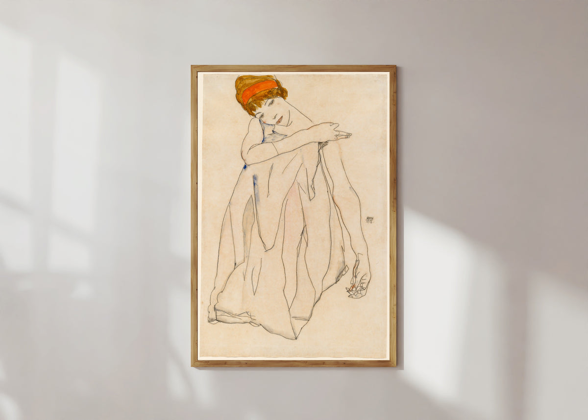 Framed art print of Dancer (Die Tänzerin) by Egon Schiele, in a light wood frame on a sunlit white wall