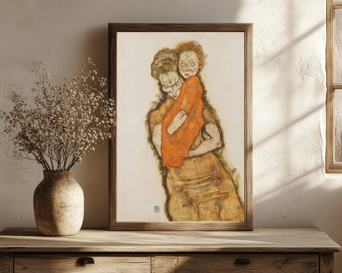 Framed art print of Mother and Child by Egon Schiele, in a dark wood frame leaning on a rustic console beside dried flowers