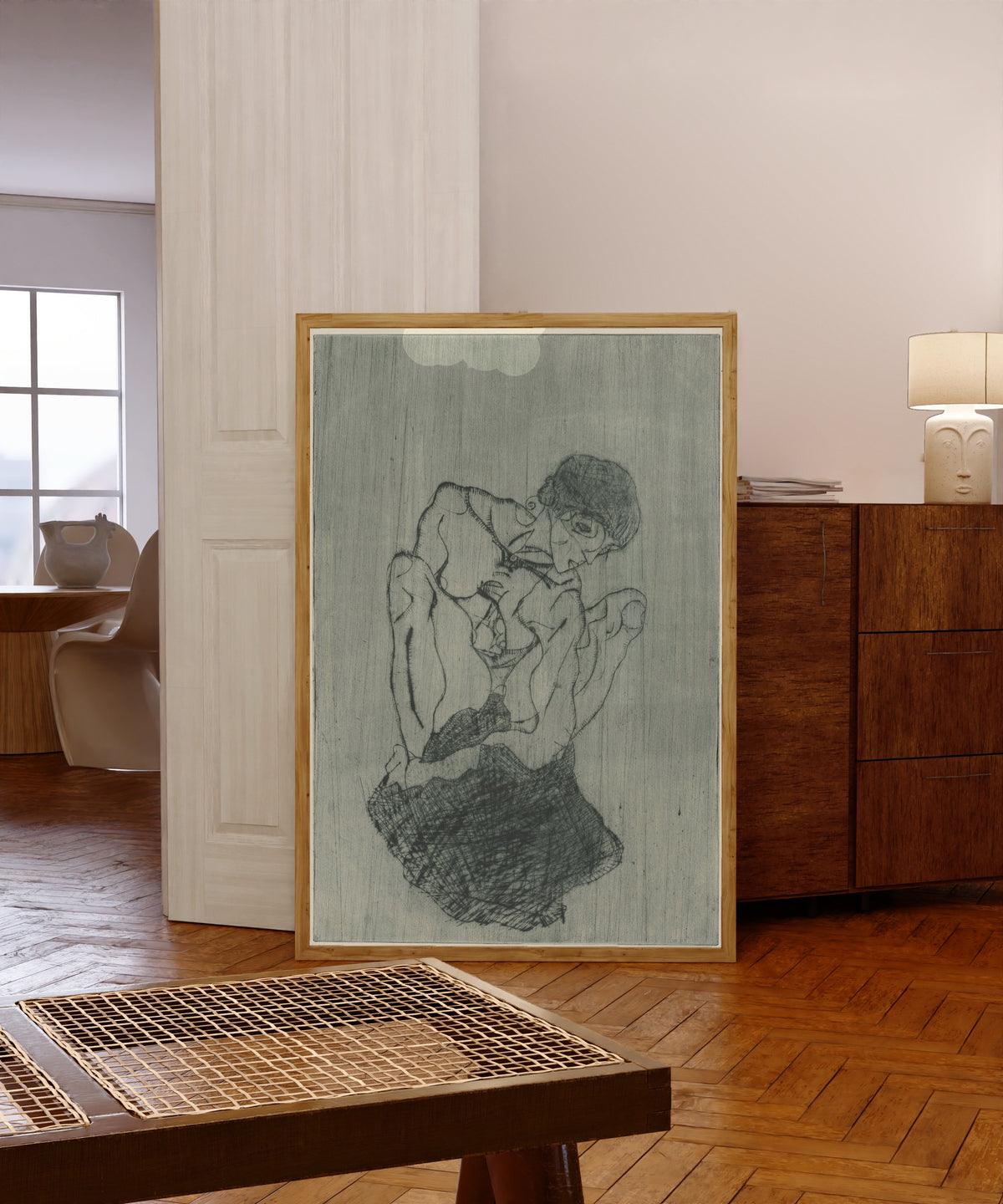 Framed art print of Sorrow (Kümmernis) by Egon Schiele, in a light wood frame leaning in a warm room with a parquet floor