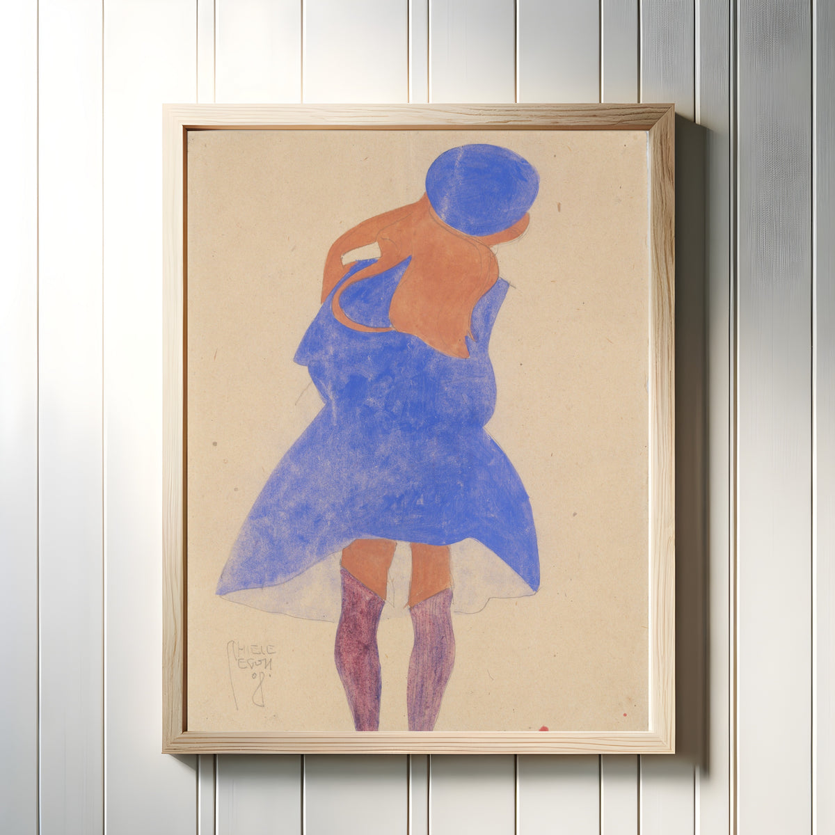 Framed art print of Standing Girl, Back View by Egon Schiele, in a light wood frame on a white panelled wall