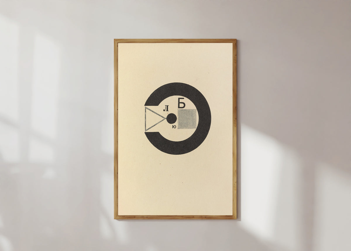 Framed art print of For the Voice: Black Ring with Letters by El Lissitzky, in a light wood frame on a sunlit white wall