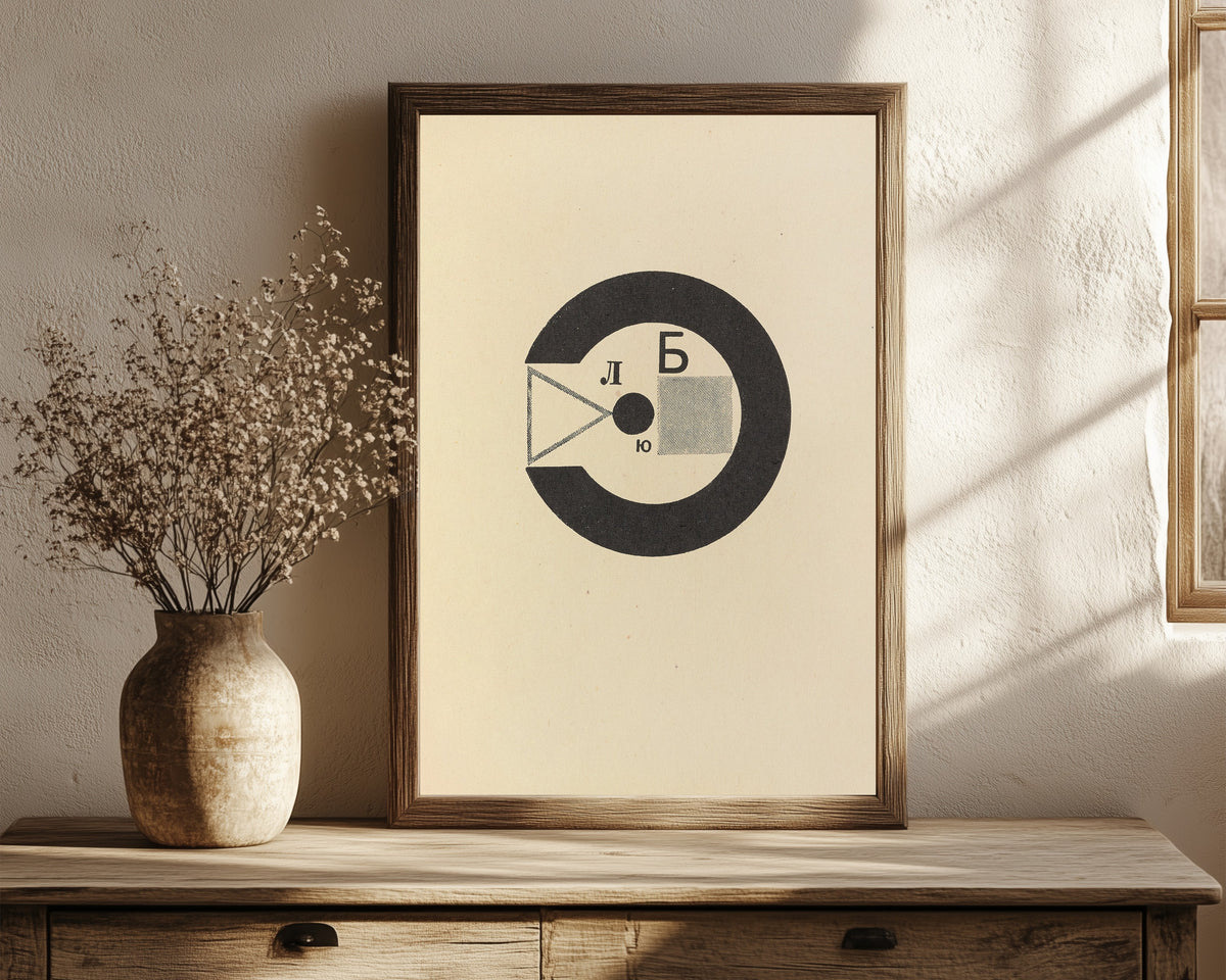 Framed art print of For the Voice: Black Ring with Letters by El Lissitzky, in a dark wood frame leaning on a rustic console beside dried flowers