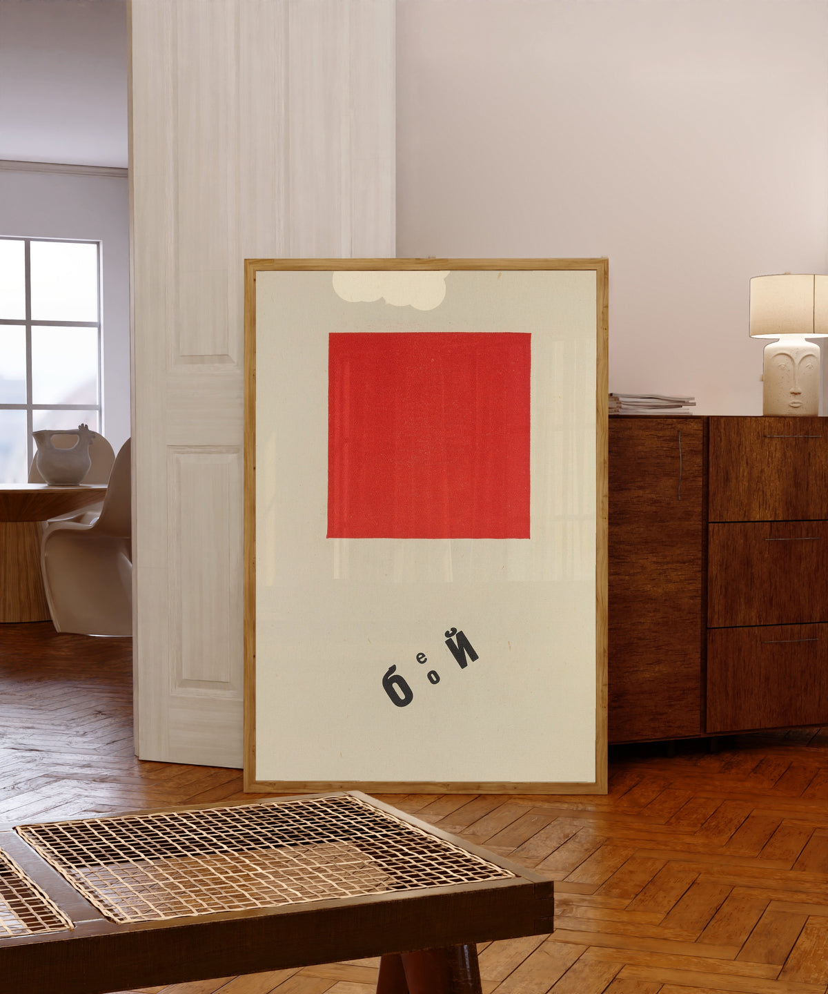 Framed art print of For the Voice: Our March (Illustration) by El Lissitzky, in a light wood frame leaning in a warm room with a parquet floor