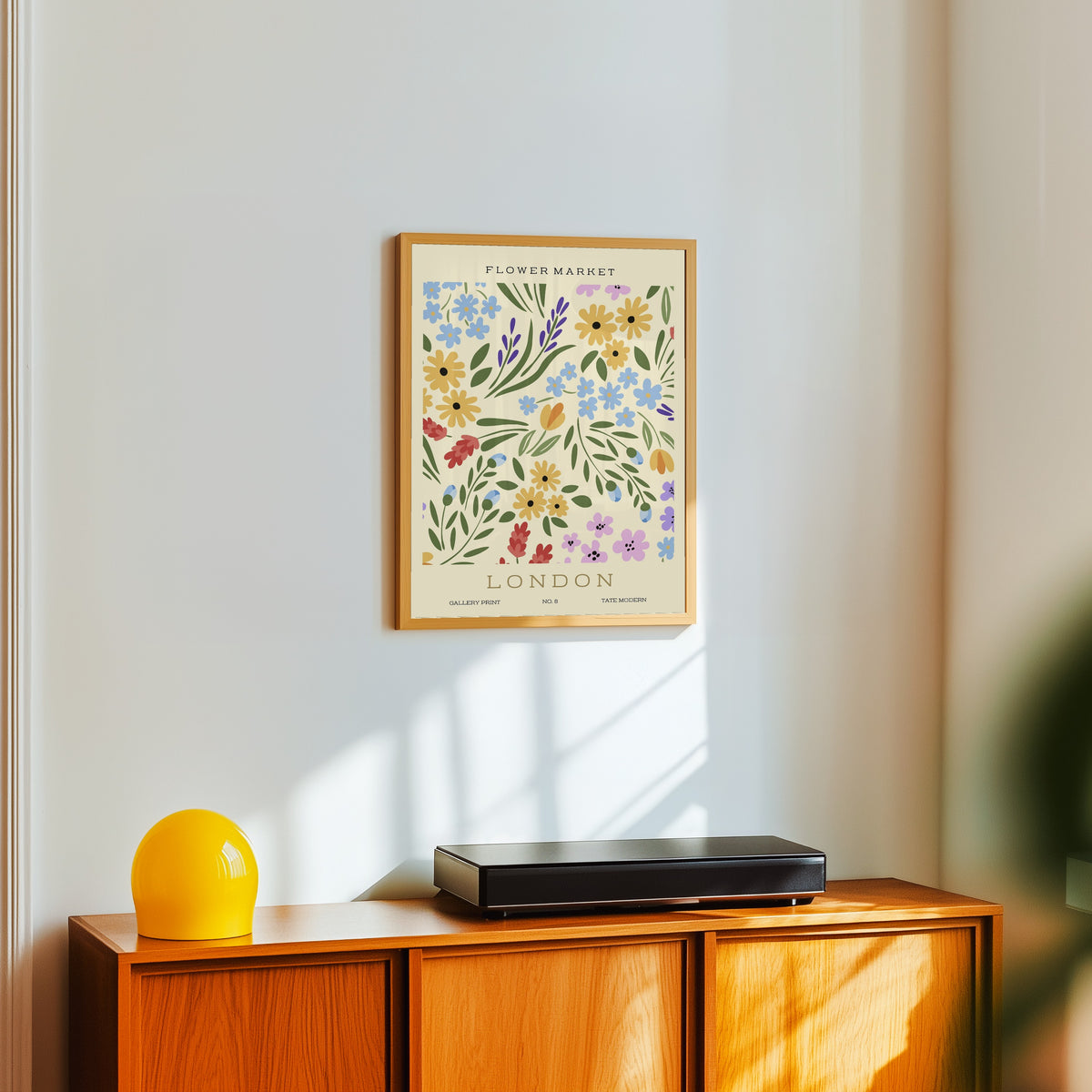 Framed art print of London by Original, in a light wood frame on a white wall above an orange sideboard