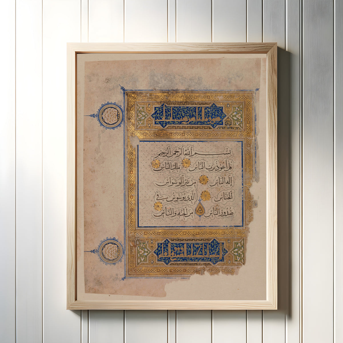 Framed art print of Folio from a Qur'an Manuscript, in a light wood frame on a white panelled wall