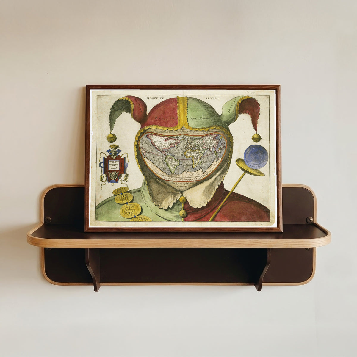 Framed art print of Fool's Cap Map of the World, in a dark wood frame resting on a wall shelf