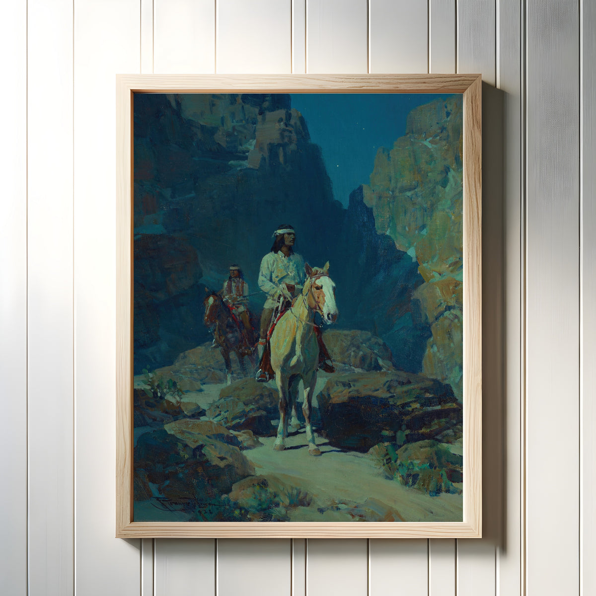 Framed art print of Moonlight in the Canyon by Frank Tenney Johnson, in a light wood frame on a white panelled wall