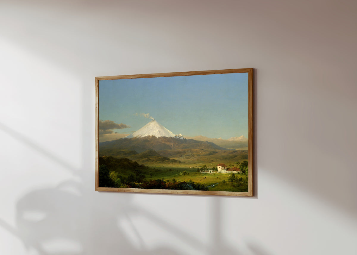 Framed art print of Cotopaxi by Frederic Edwin Church, in a light wood frame on a sunlit white wall, seen at a slight angle