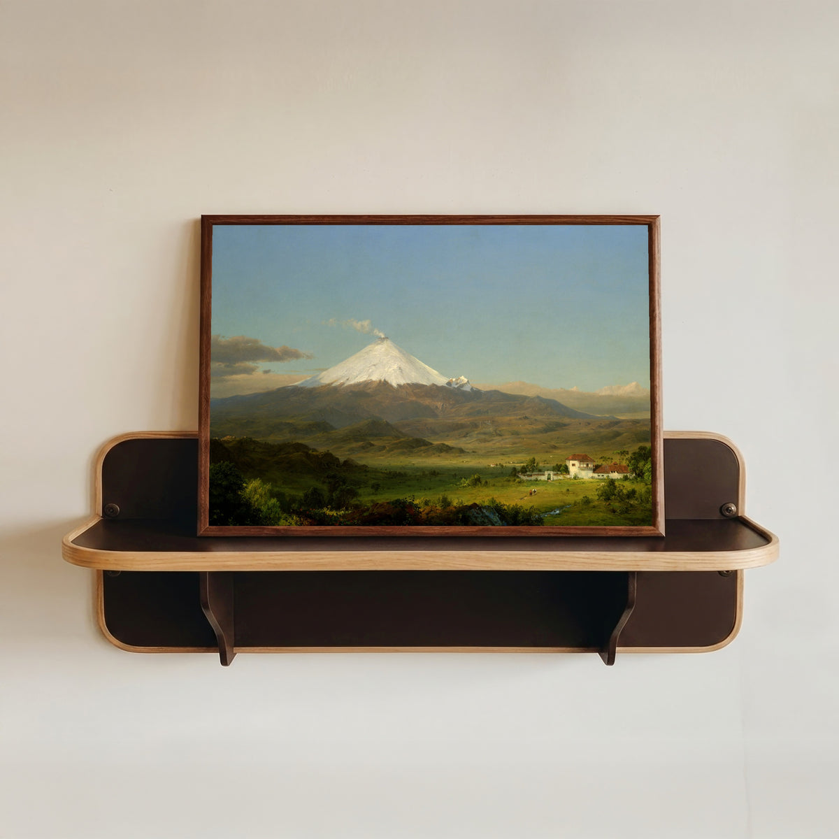 Framed art print of Cotopaxi by Frederic Edwin Church, in a dark wood frame resting on a wall shelf