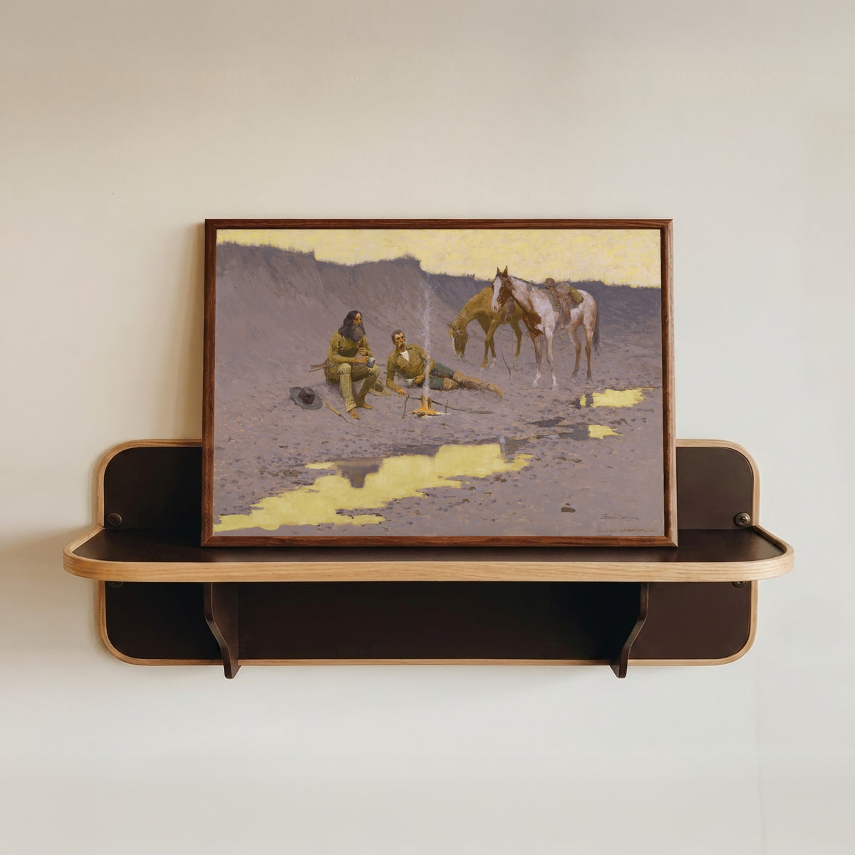 Framed art print of A New Year on the Cimarron by Frederic Remington, in a dark wood frame resting on a wall shelf