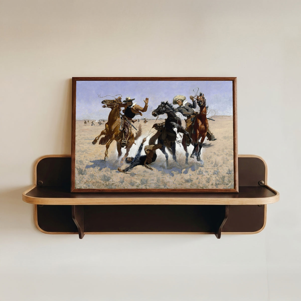 Framed art print of Aiding a Comrade by Frederic Remington, in a dark wood frame resting on a wall shelf