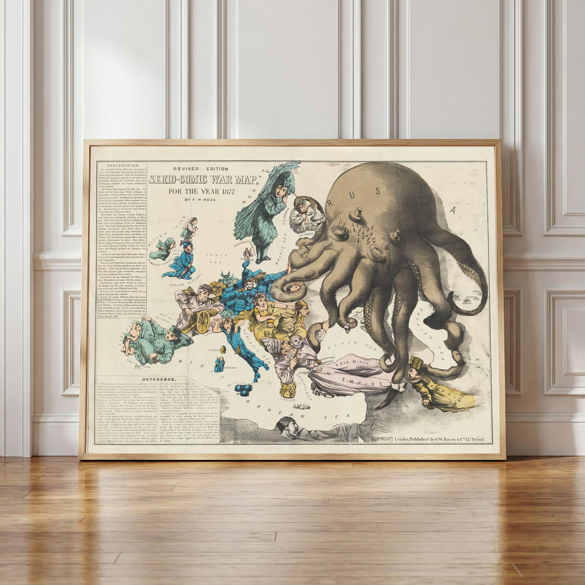 Framed art print of Serio-Comic War Map for the Year 1877 by Frederick W. Rose, in a light wood frame leaning against a panelled white wall