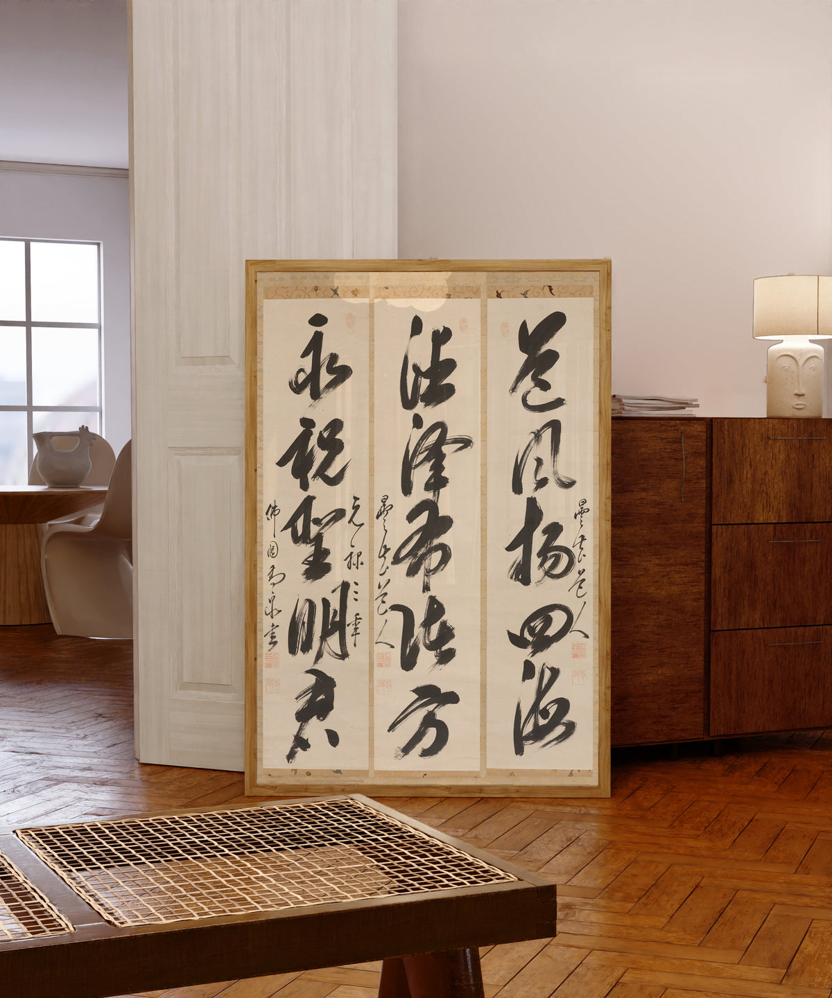 Framed art print of Calligraphy Triptych by Gaoquan Xingdun, in a light wood frame leaning in a warm room with a parquet floor