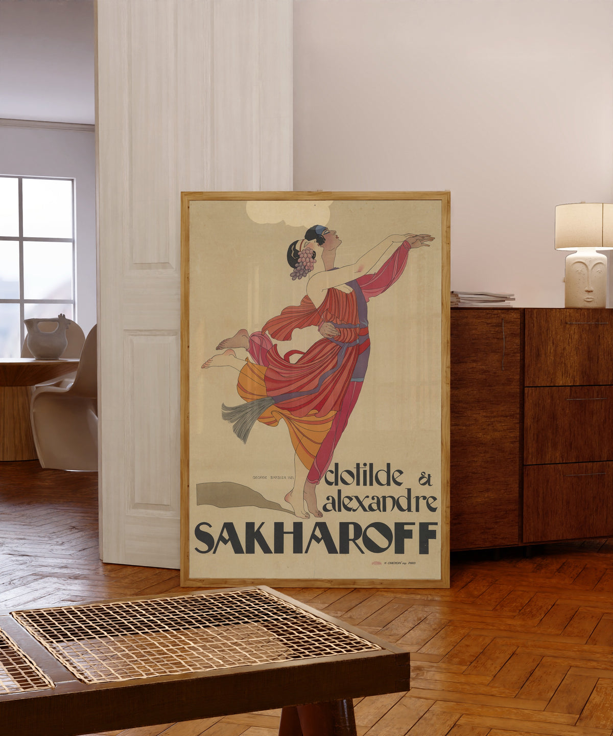 Framed art print of Clotilde et Alexandre Sakharoff by George Barbier, in a light wood frame leaning in a warm room with a parquet floor