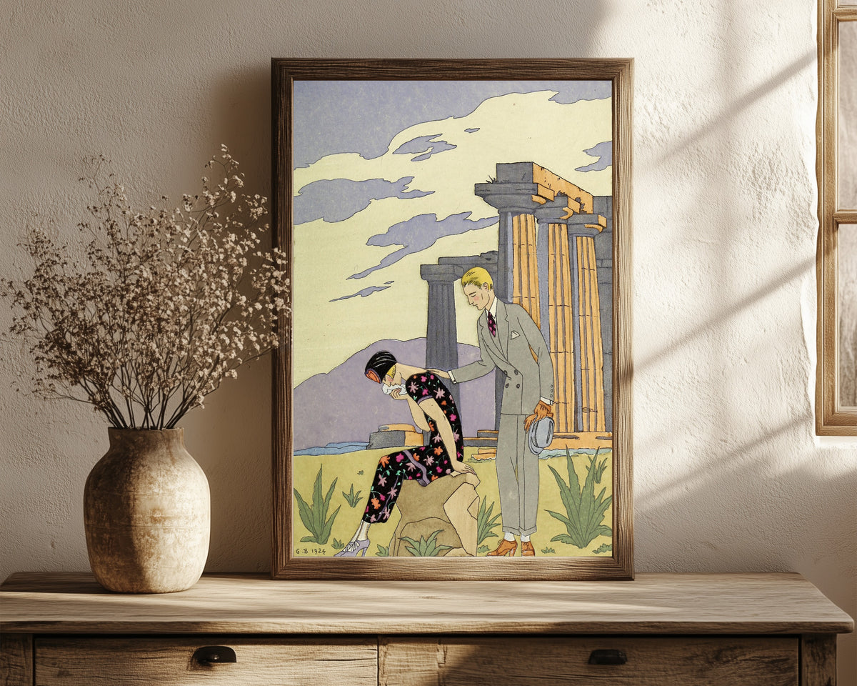 Framed art print of Falbalas et Fanfreluches: Paestum by George Barbier, in a dark wood frame leaning on a rustic console beside dried flowers