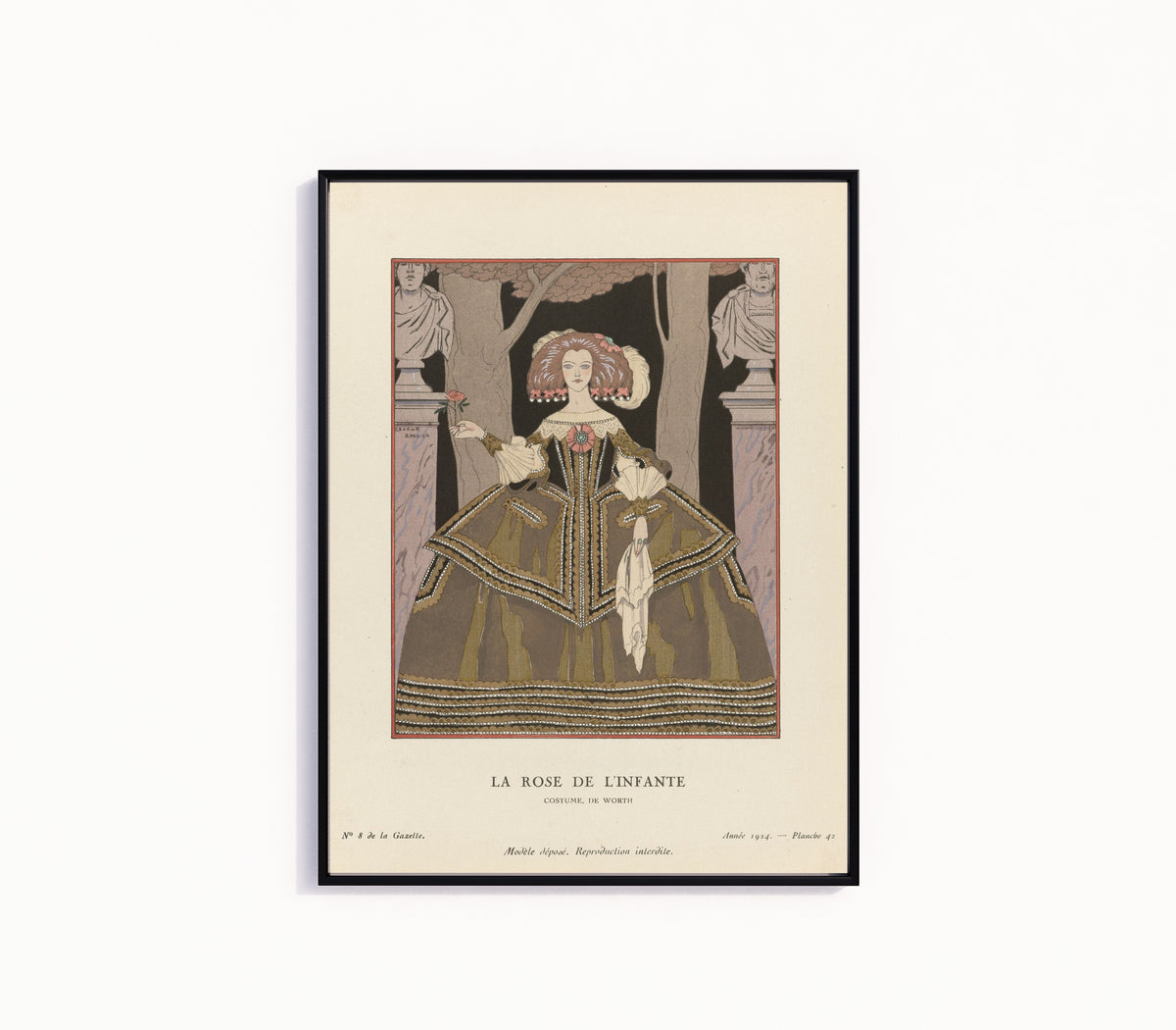 Framed art print of La Rose de l'Infante, costume de Worth by George Barbier, in a slim black frame on a plain white wall