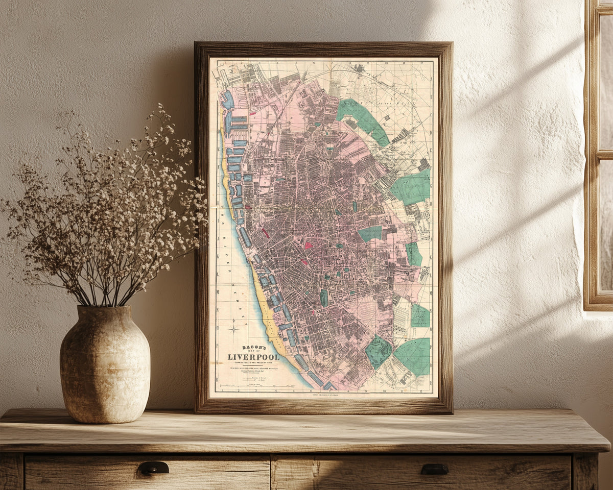 Framed art print of Bacon's Map of Liverpool by George Washington Bacon, in a dark wood frame leaning on a rustic console beside dried flowers