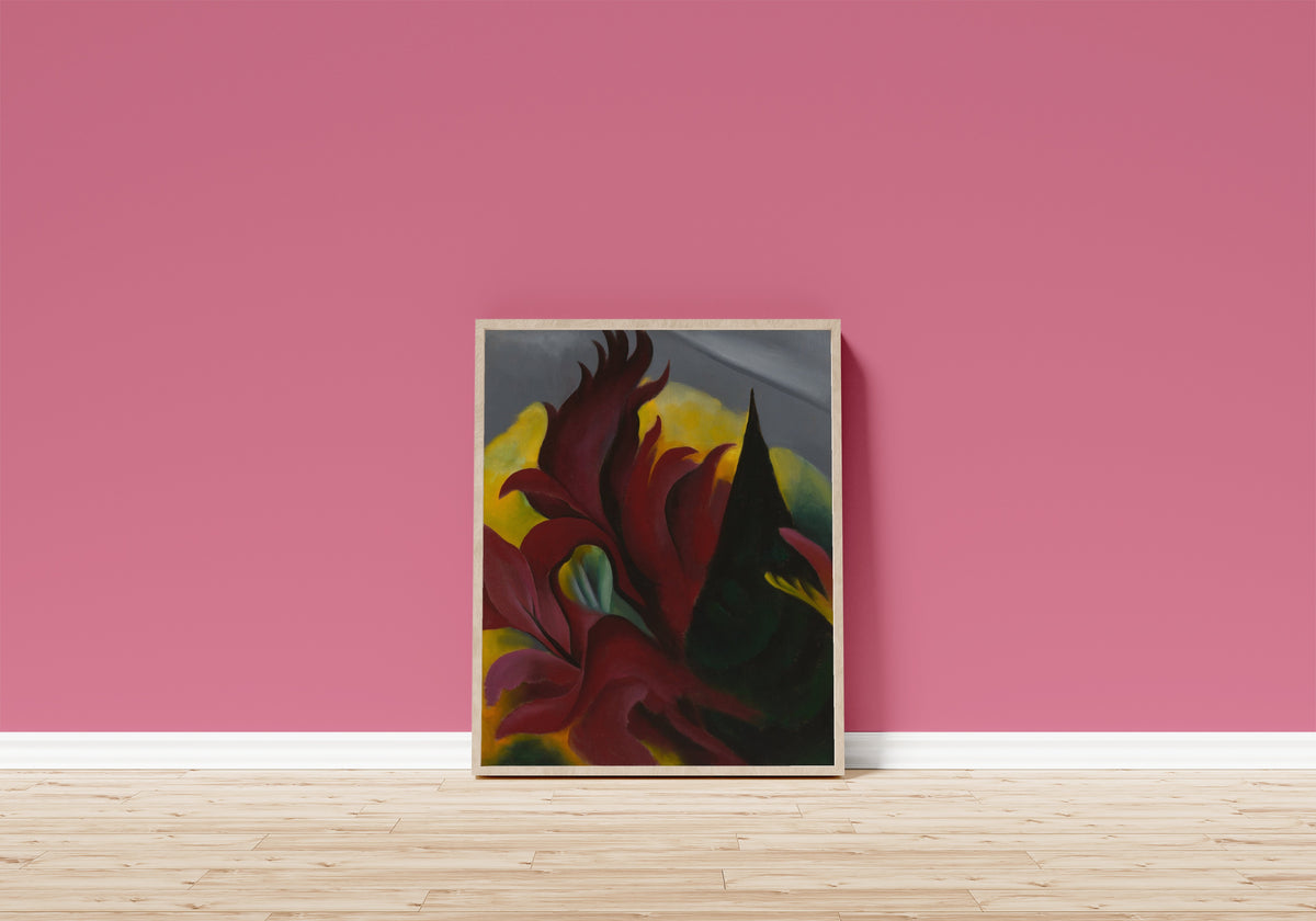 Framed art print of Red Maple by Georgia O'Keeffe, in a light wood frame leaning on a pink wall above a wooden floor