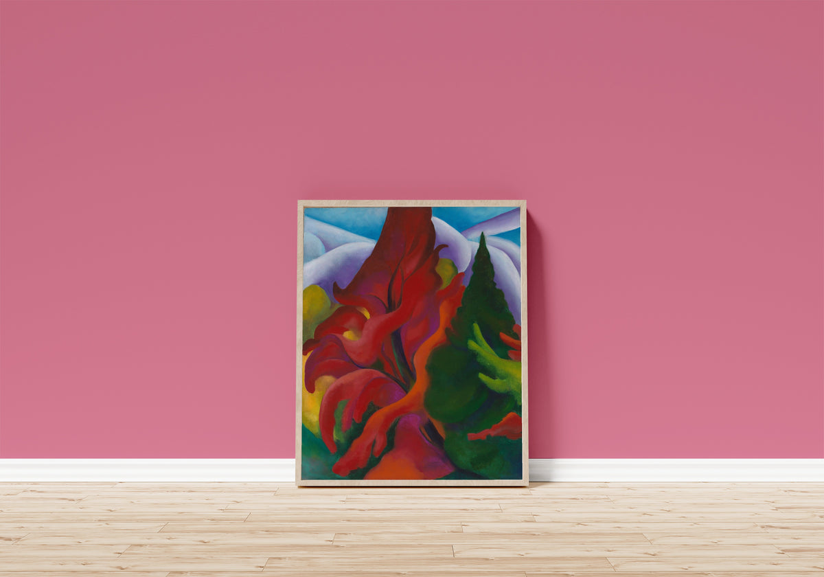 Framed art print of Trees in Autumn by Georgia O'Keeffe, in a light wood frame leaning on a pink wall above a wooden floor
