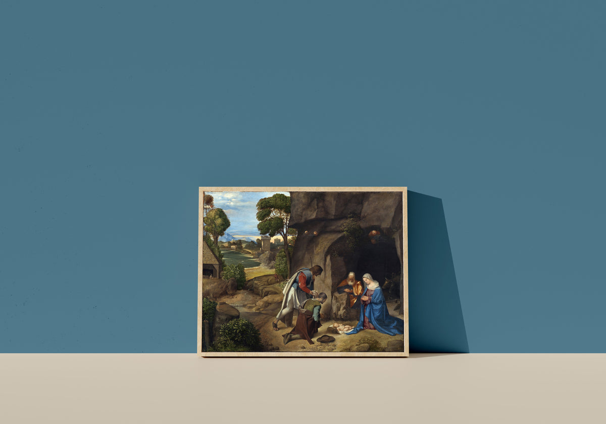 Framed art print of The Adoration of the Shepherds by Giorgione, in a light wood frame leaning on a blue wall