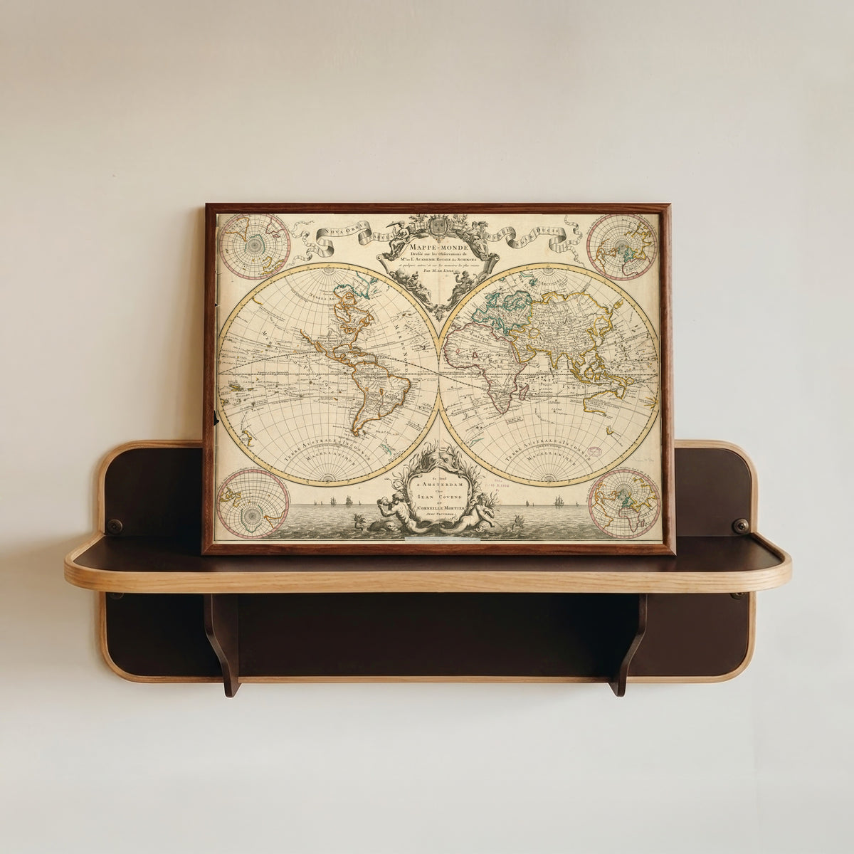 Framed art print of Mappe-Monde by Guillaume Delisle, in a dark wood frame resting on a wall shelf