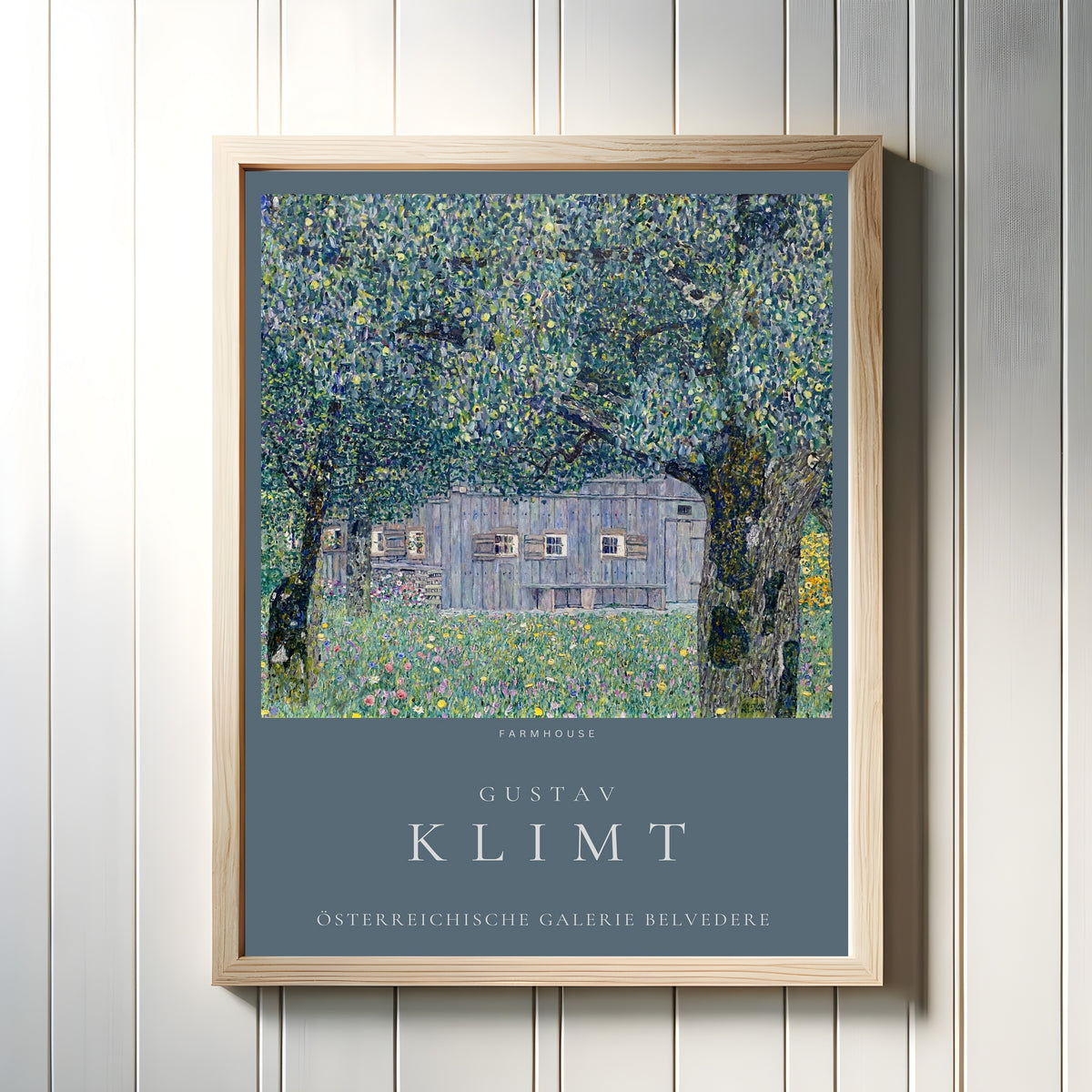 Framed art print of Farmhouse in Upper Austria by Gustav Klimt, in a light wood frame on a white panelled wall