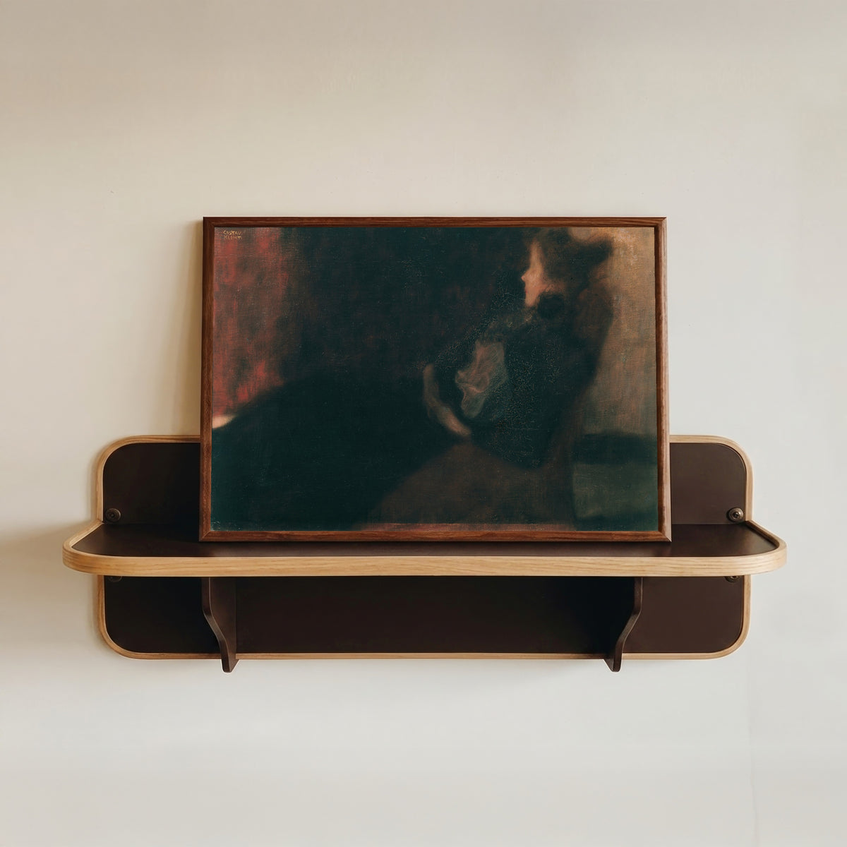 Framed art print of Lady by the Fireplace (Dame am Kamin) by Gustav Klimt, in a dark wood frame resting on a wall shelf