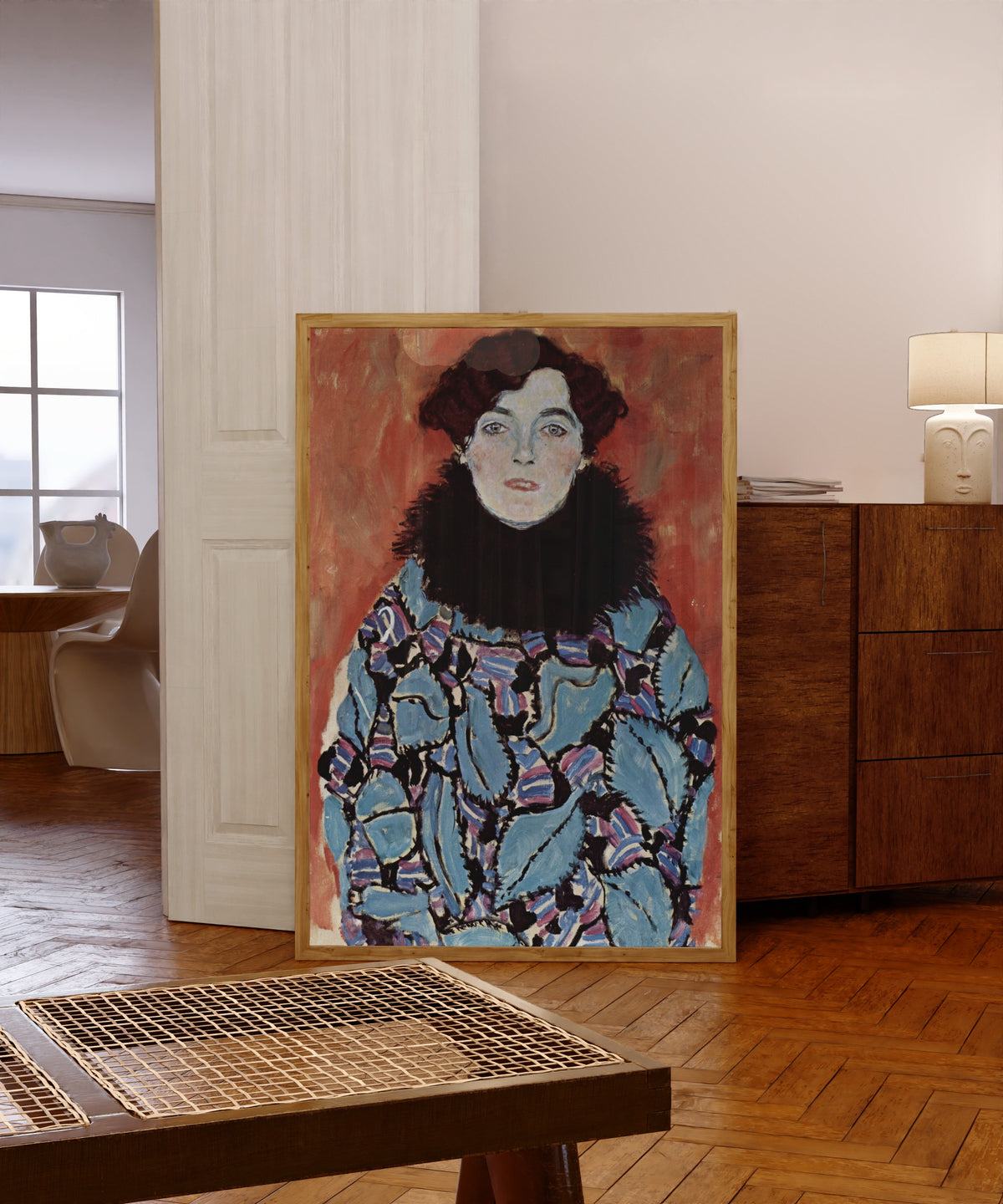 Framed art print of Portrait of Johanna Staude by Gustav Klimt, in a light wood frame leaning in a warm room with a parquet floor